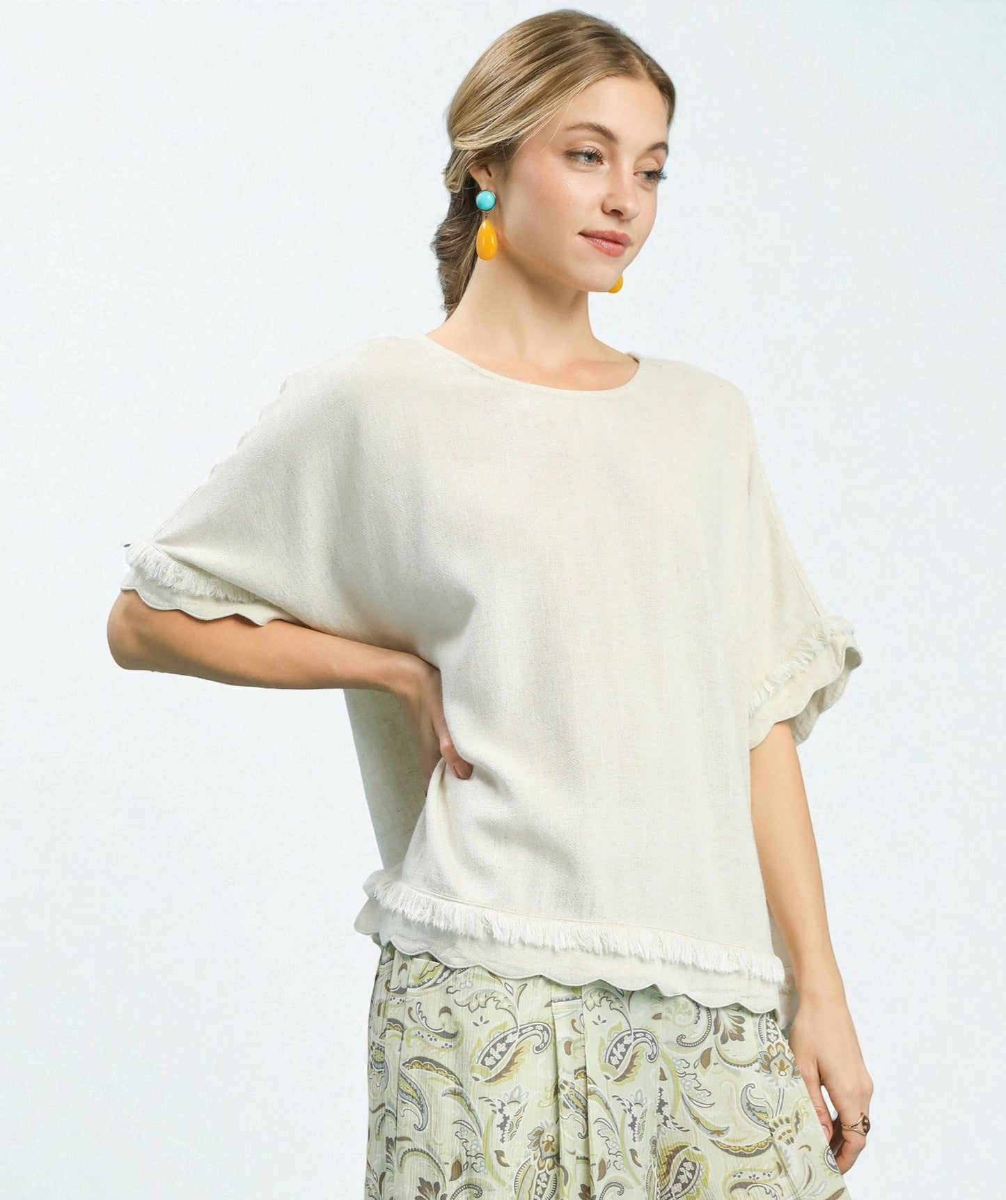 Woman wearing a white top and patterned pants on a light gray background