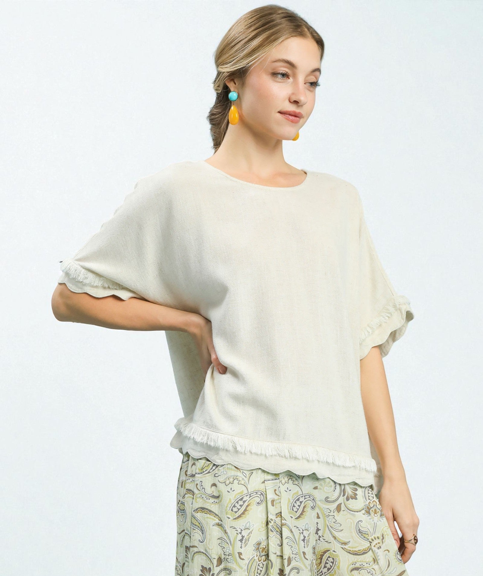 Woman wearing a white top and patterned pants on a light gray background