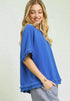 Woman wearing a blue top with ruffled sleeves against a light background