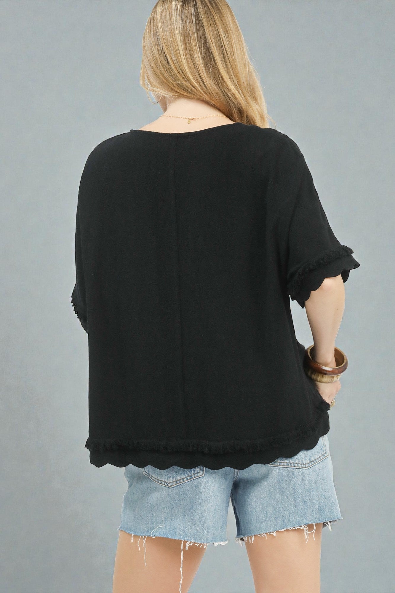 Person wearing a black top and denim shorts on a gray background