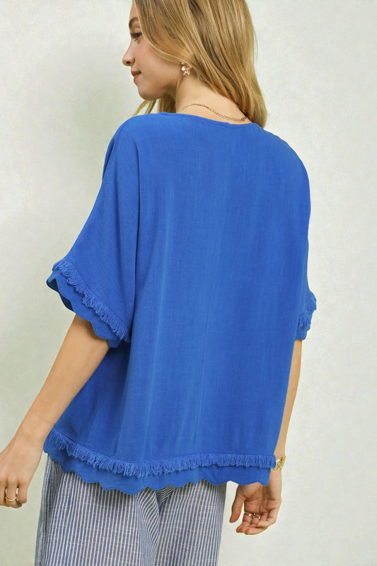 Woman wearing a blue blouse with ruffled sleeves on a plain background