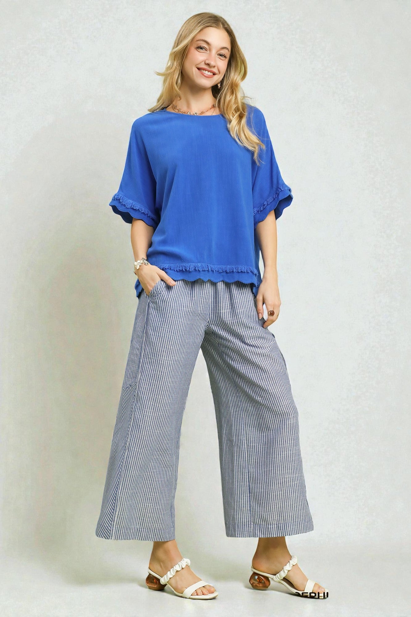 Woman wearing a blue top and checkered pants on a plain background