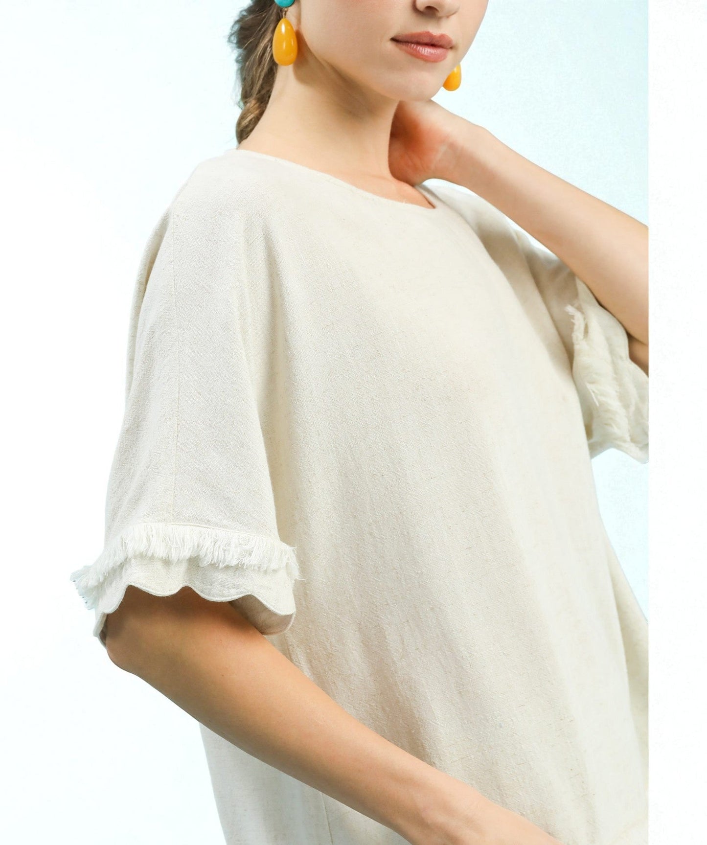 Woman wearing a beige off-shoulder top with ruffled sleeves on a white background