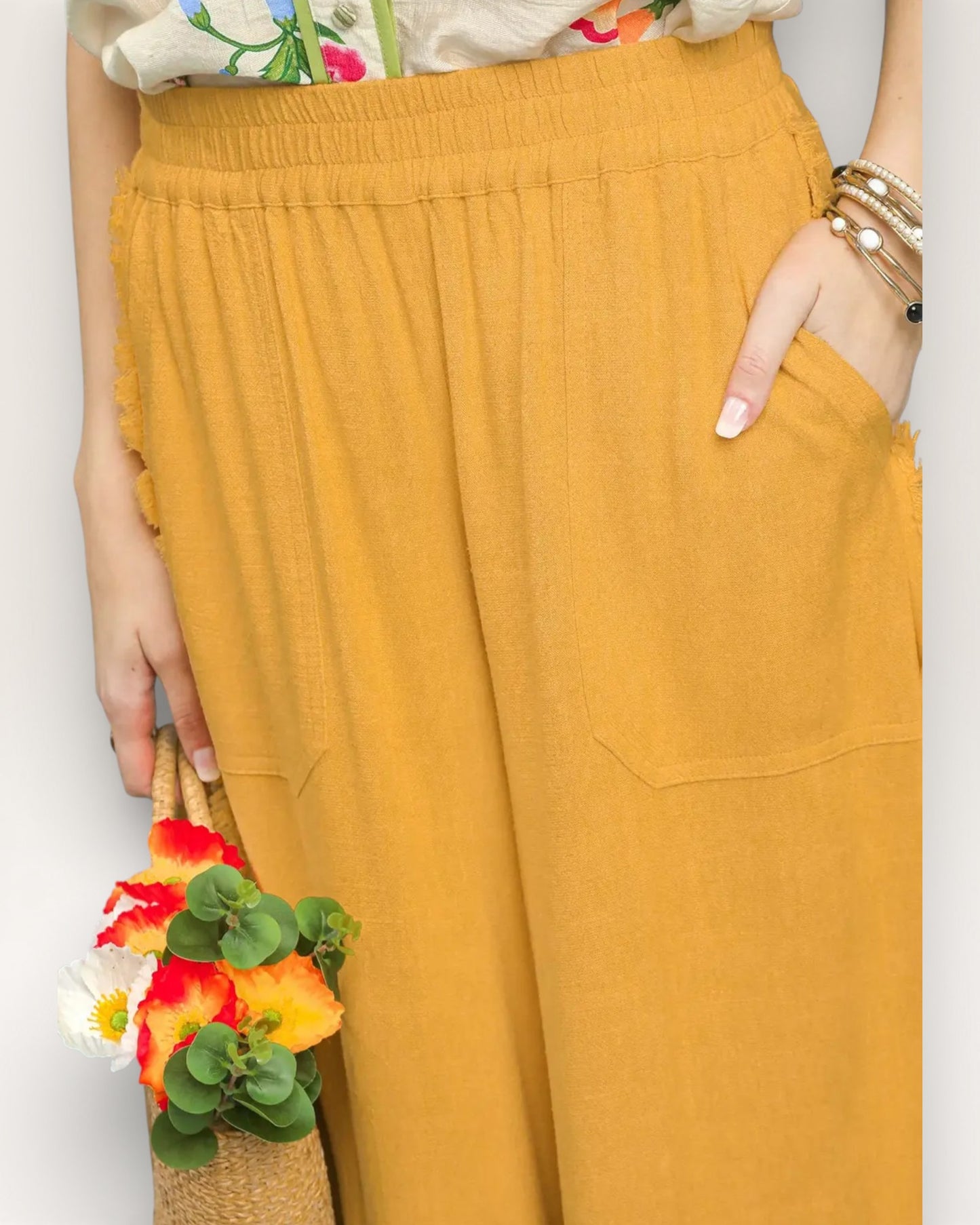 Mustard yellow pants worn by a person with a colorful top and floral arrangement.
