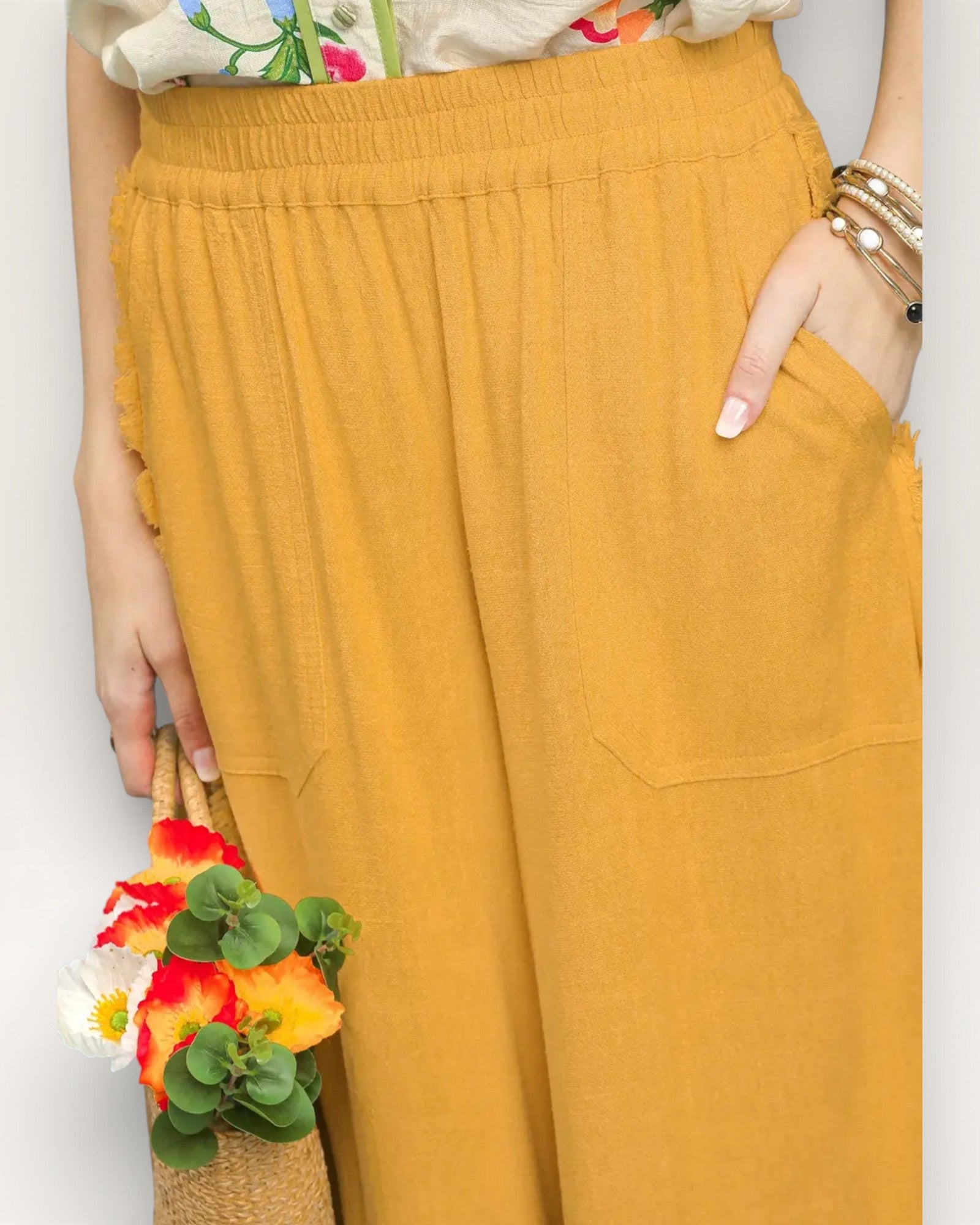 Mustard yellow pants worn by a person with a colorful top and floral arrangement.