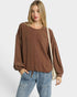 Woman wearing a brown oversized sweater and blue jeans on a white background