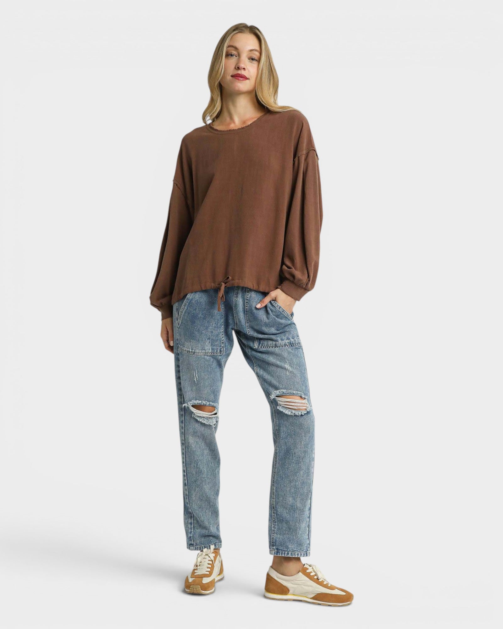 Woman wearing a brown sweater and blue jeans on a white background