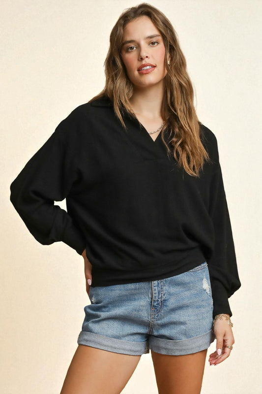 Woman wearing a black sweater and denim shorts on a beige background