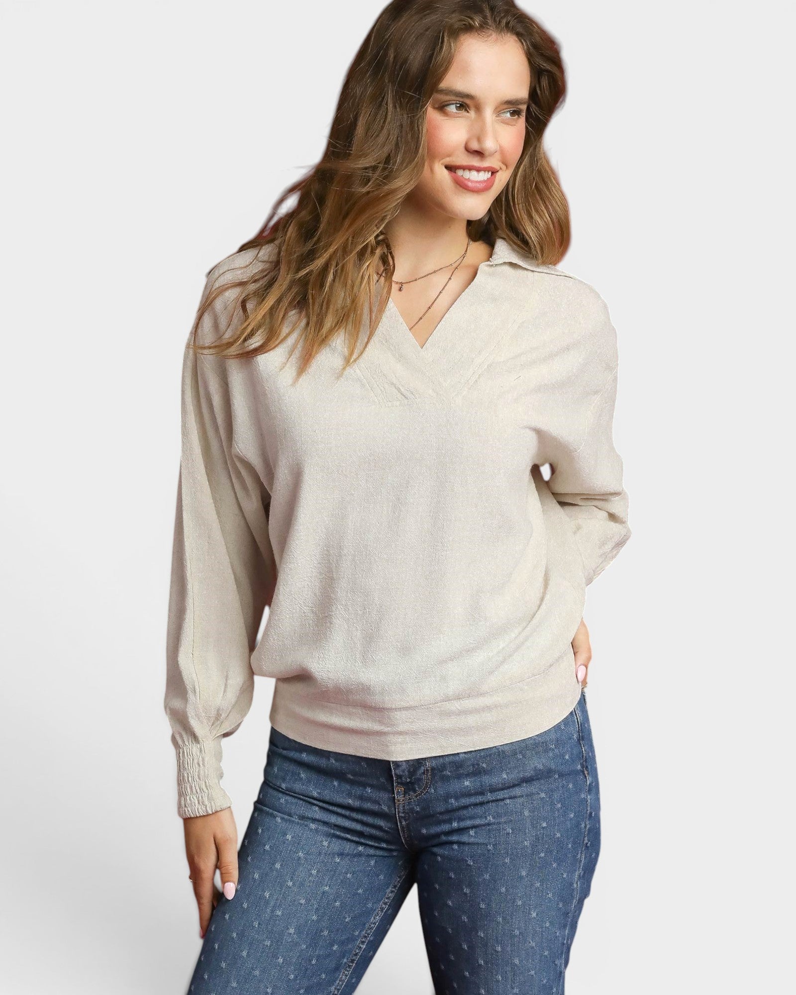 Woman wearing a beige sweater and blue jeans on a white background