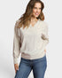 Woman wearing a beige sweater and blue jeans on a white background