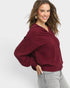 Woman wearing a burgundy sweater and gray pants on a white background
