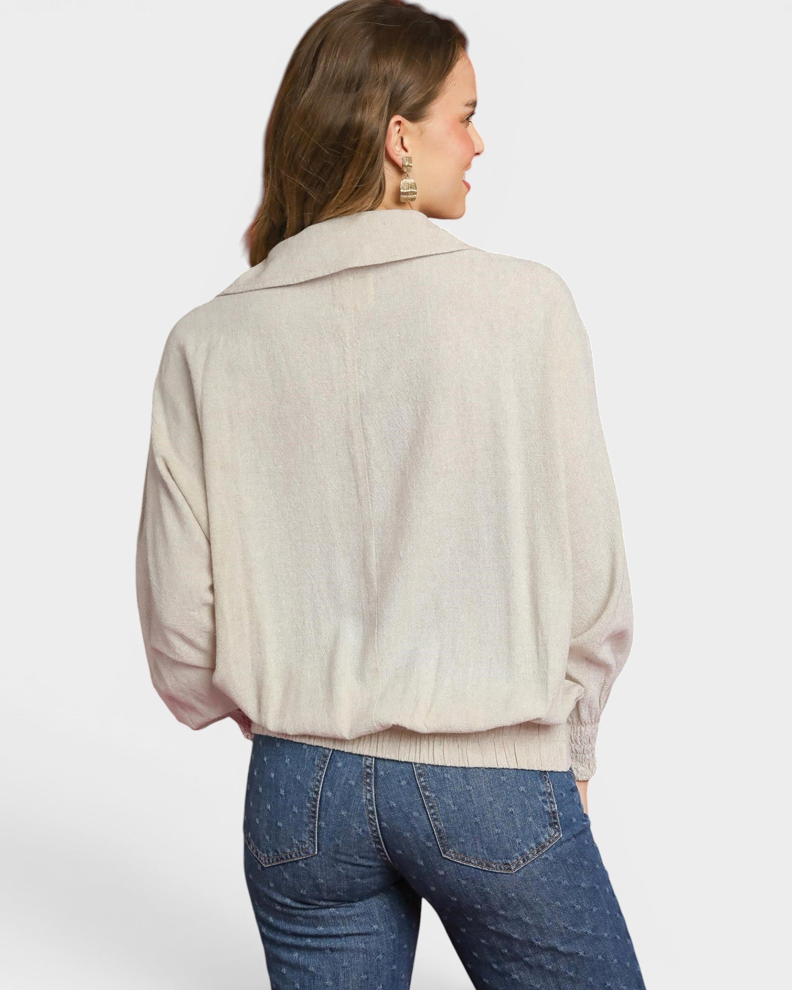 Woman wearing a beige blouse and blue jeans on a white background