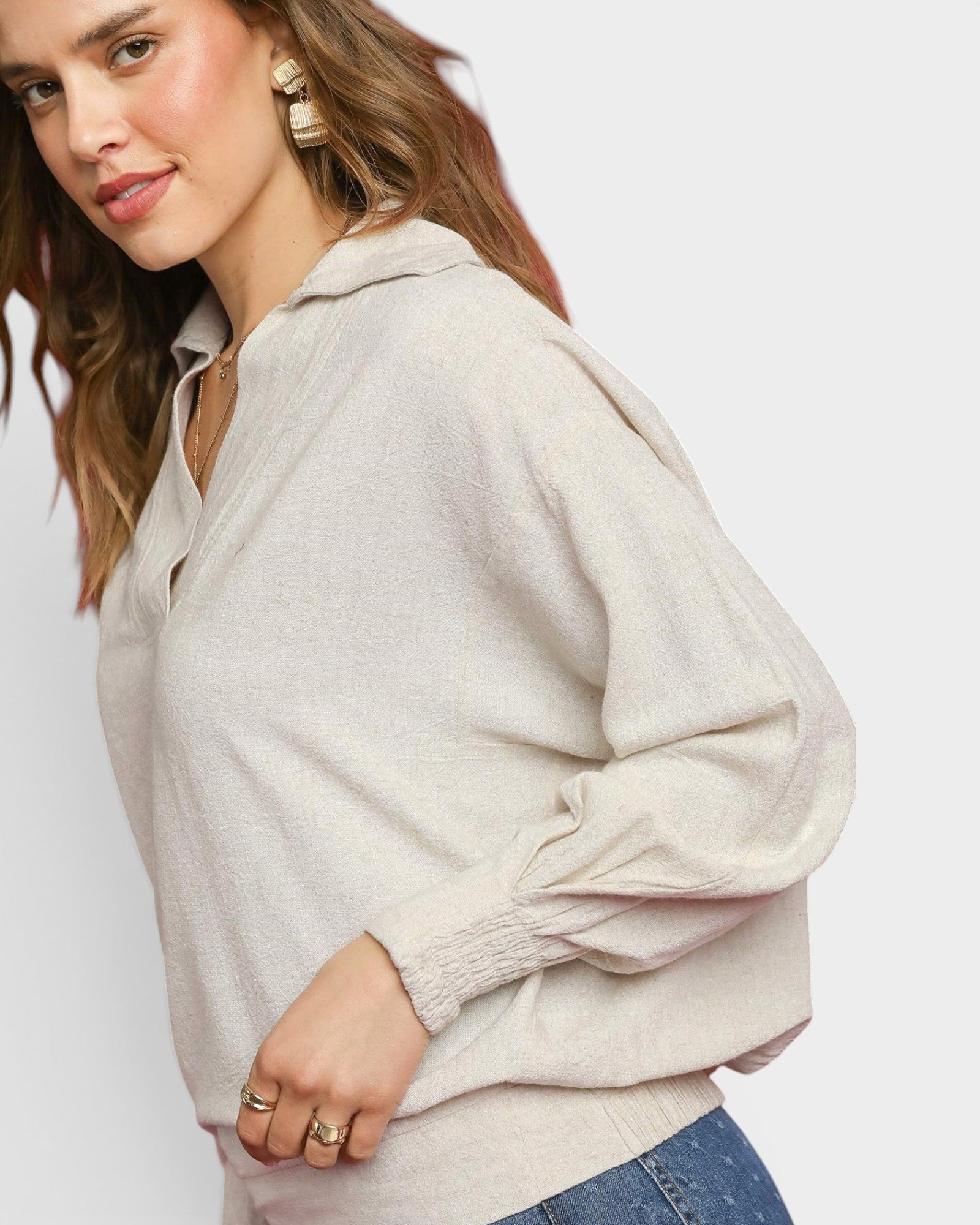 Woman wearing a beige oversized hoodie on a plain background