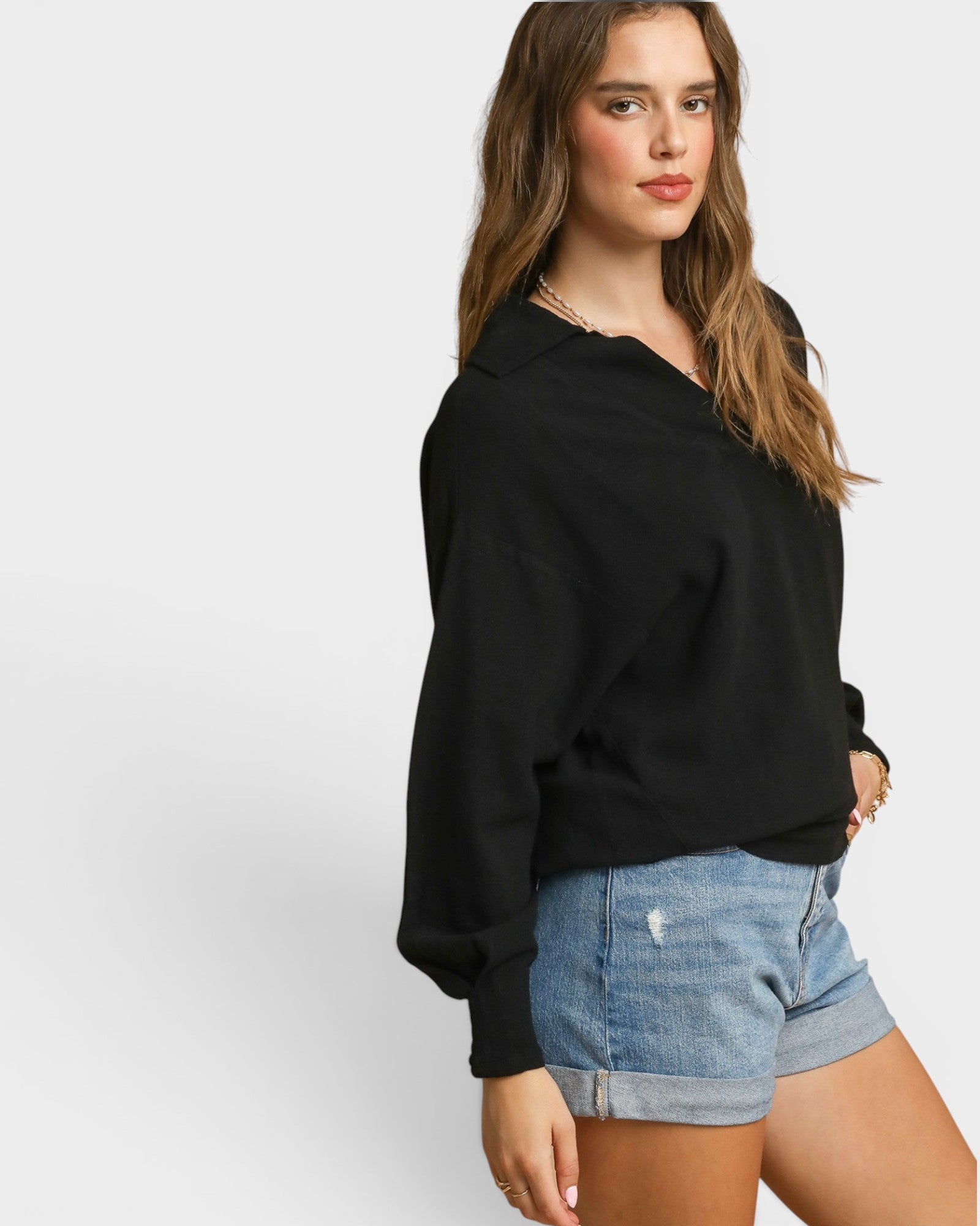 Woman wearing a black sweater and denim shorts on a white background