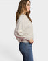 Woman wearing a light gray sweater and blue jeans on a white background