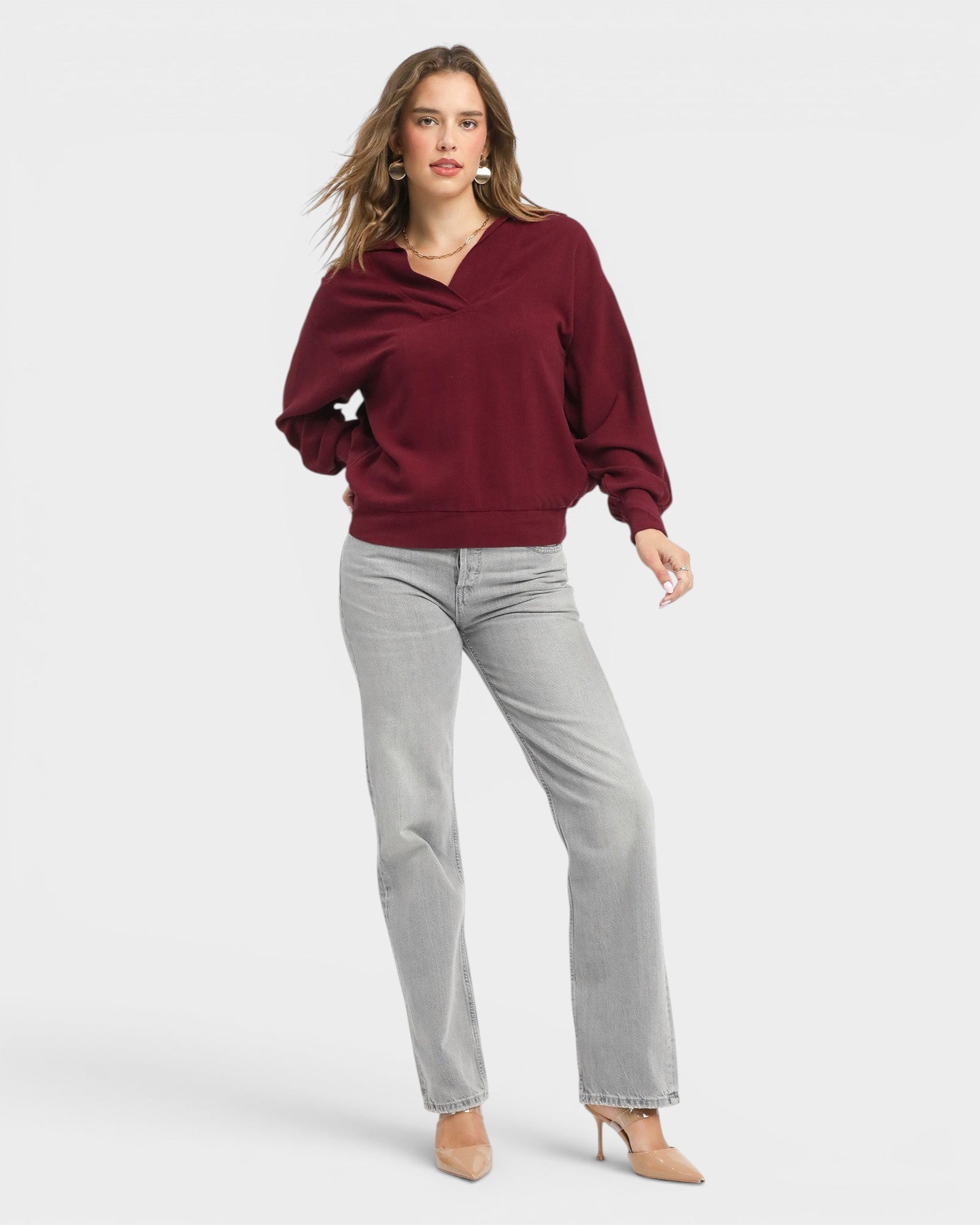 Woman wearing a burgundy sweater and gray pants on a white background