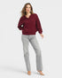 Woman wearing a burgundy sweater and gray pants on a white background