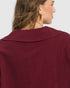 Close-up of a burgundy blouse worn by a person on a white background