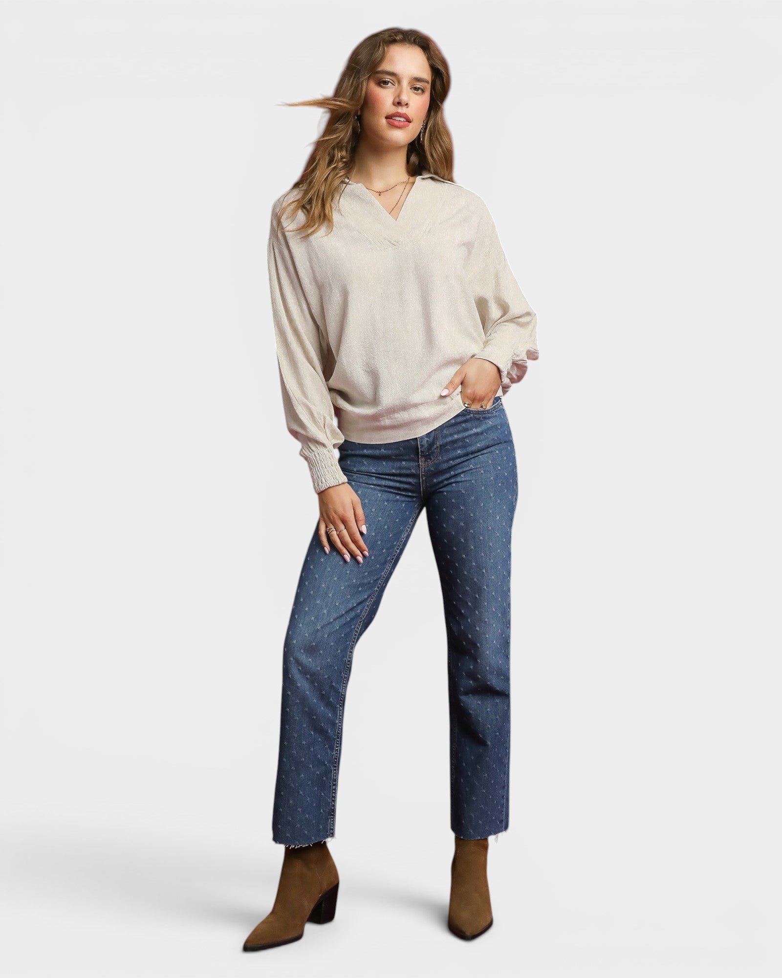 Woman wearing a beige sweater and blue jeans on a white background