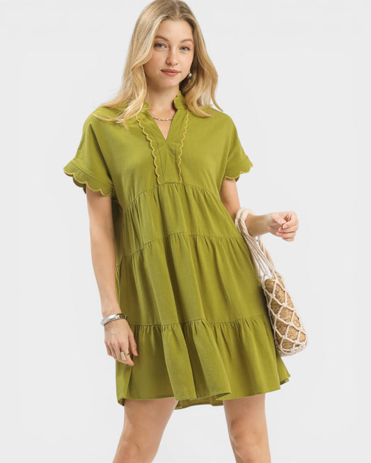 Woman wearing a green dress holding a beige bag on a white background