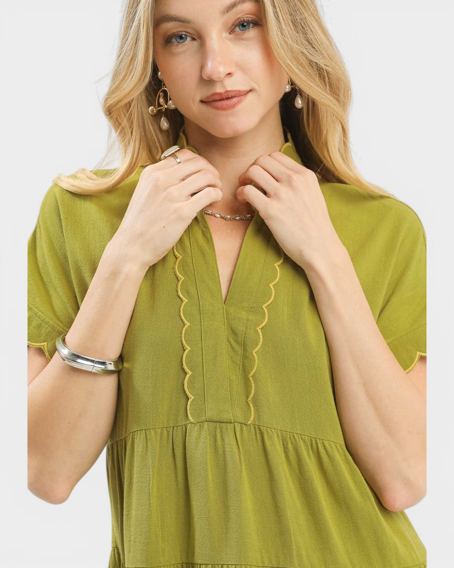 Woman wearing a green dress with ruffled details on a white background