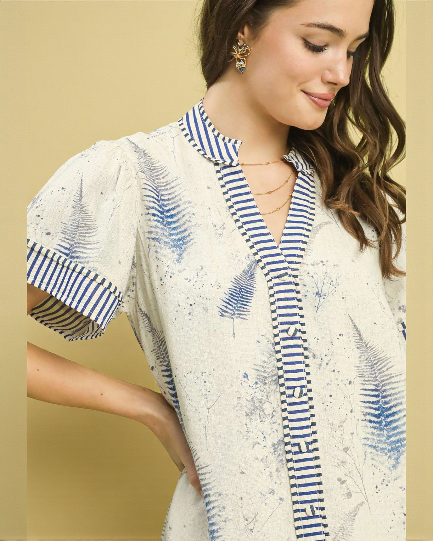 Woman wearing a white blouse with blue patterns and accents on a beige background