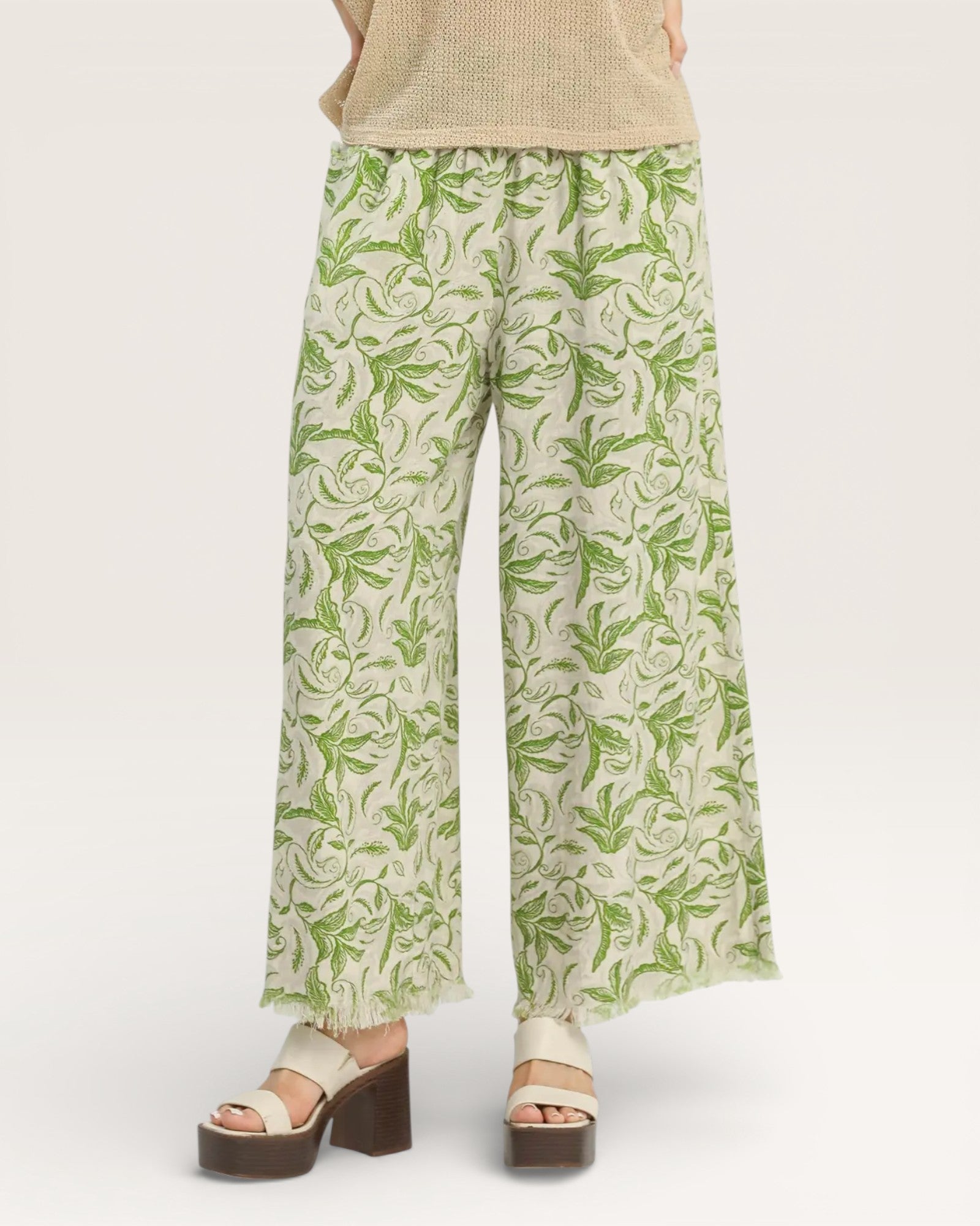 Green leaf-patterned pants worn by a person on a white background