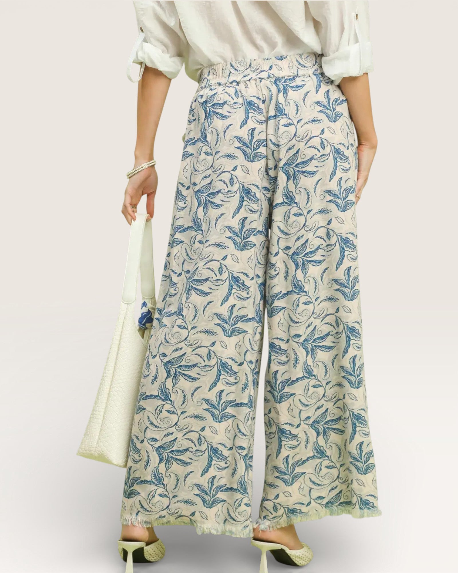 Person wearing floral-patterned pants with a plain background