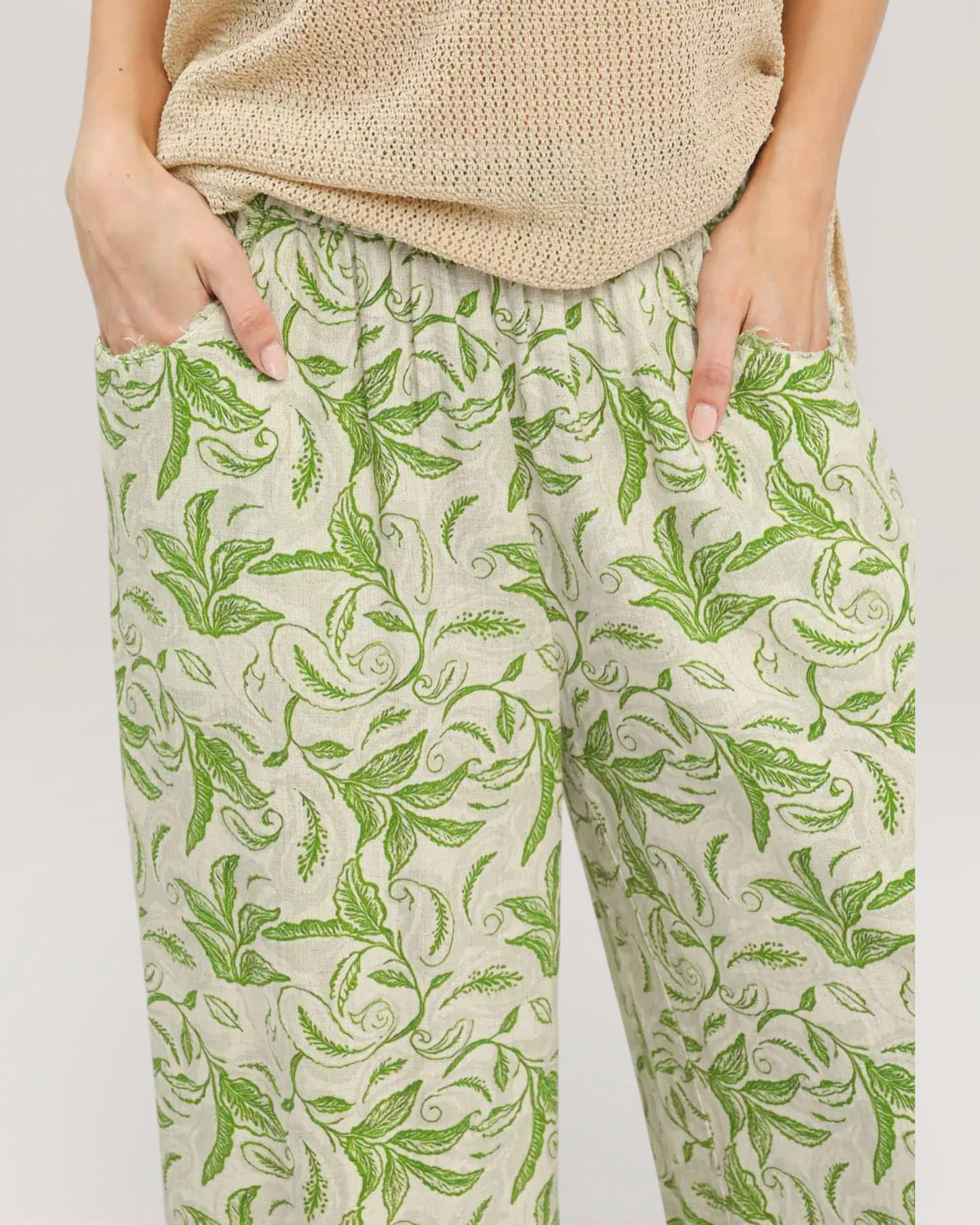 Person wearing green leaf-patterned pants on a plain background