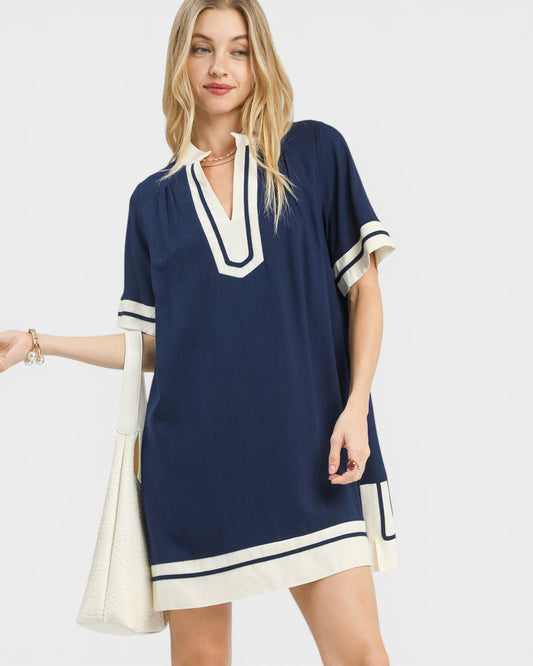 Woman wearing a navy dress with white trim on a light gray background