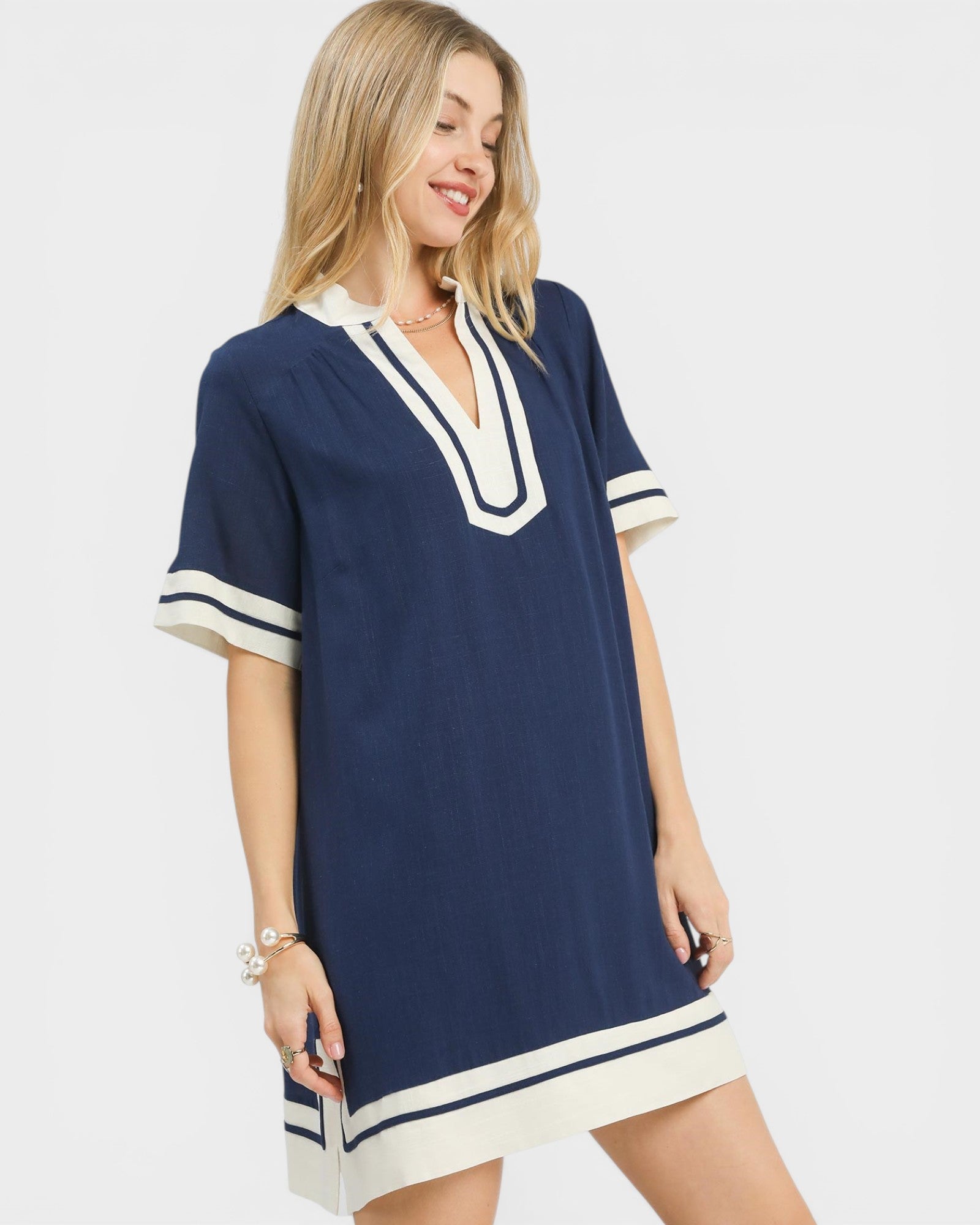 Woman wearing a navy dress with white trim on a plain background