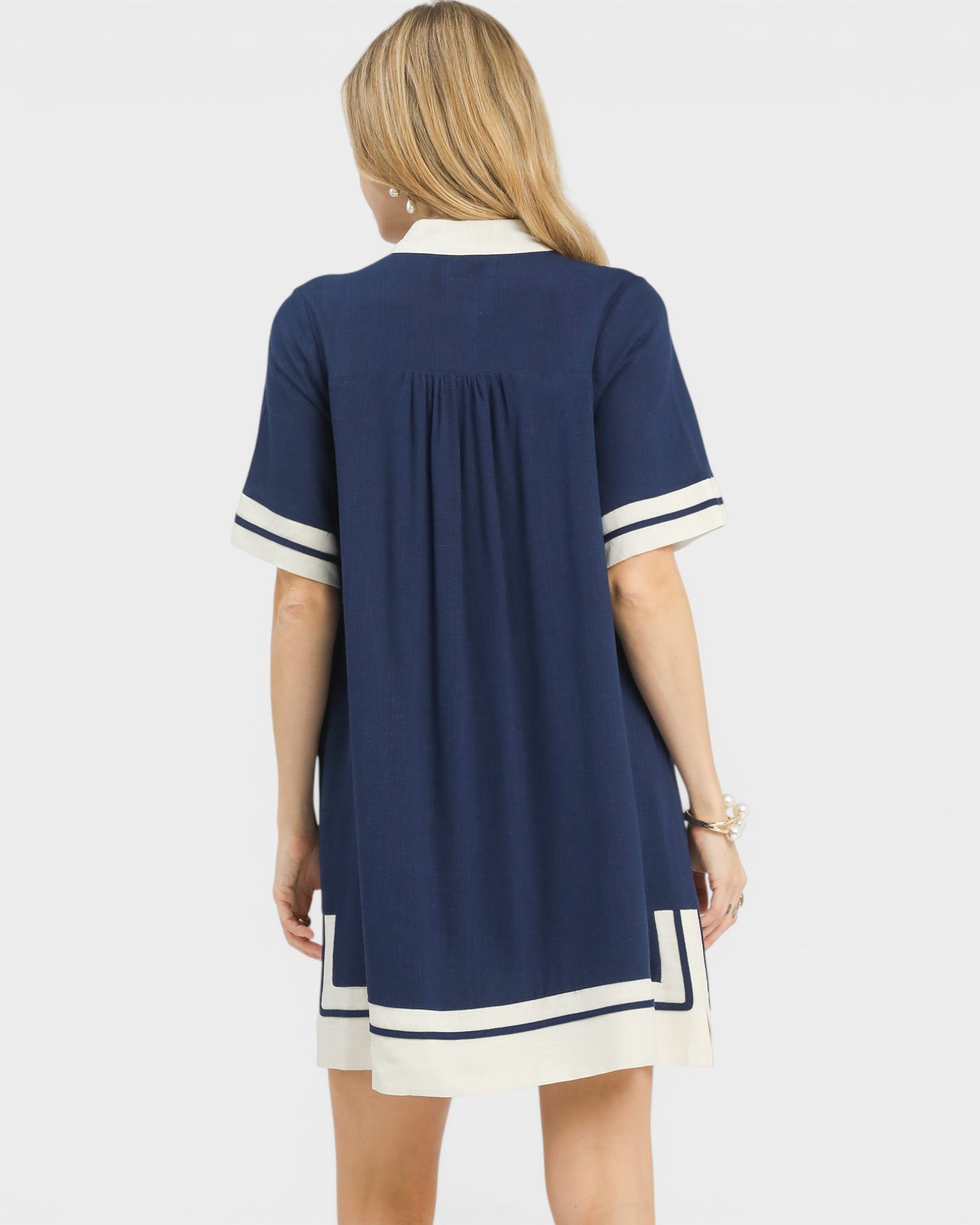 Woman wearing a navy dress with white accents on a white background