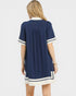 Woman wearing a navy dress with white accents on a white background
