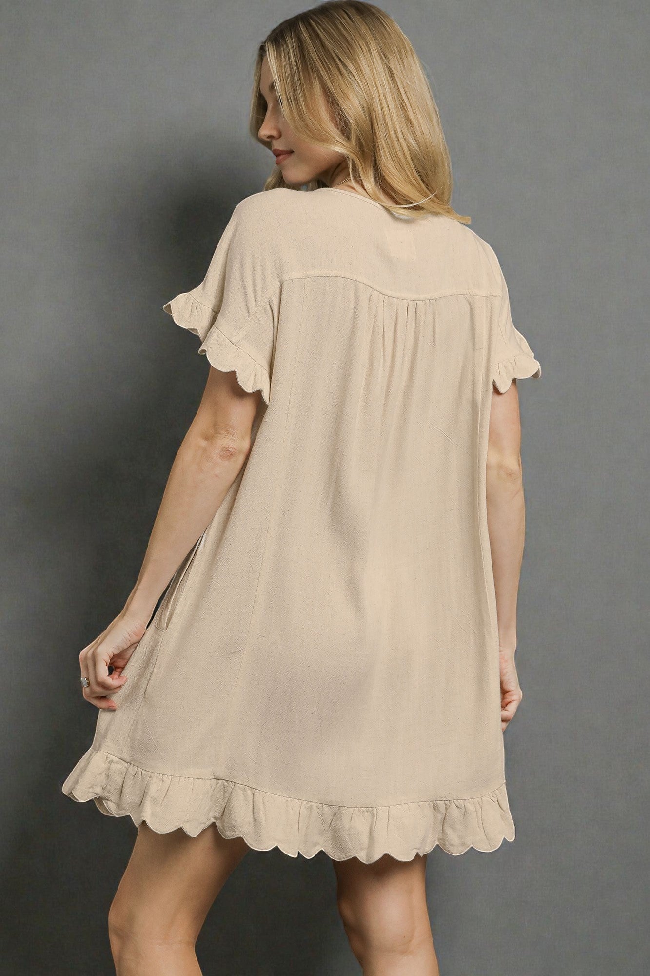 Woman wearing a beige dress against a gray background