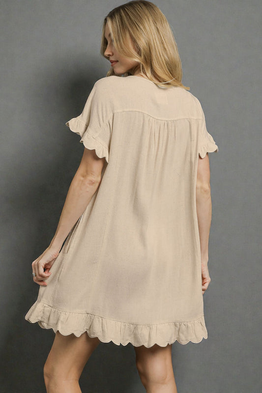 Woman wearing a beige dress against a gray background