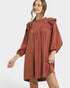 Woman wearing a rust-colored dress with ruffled sleeves on a white background