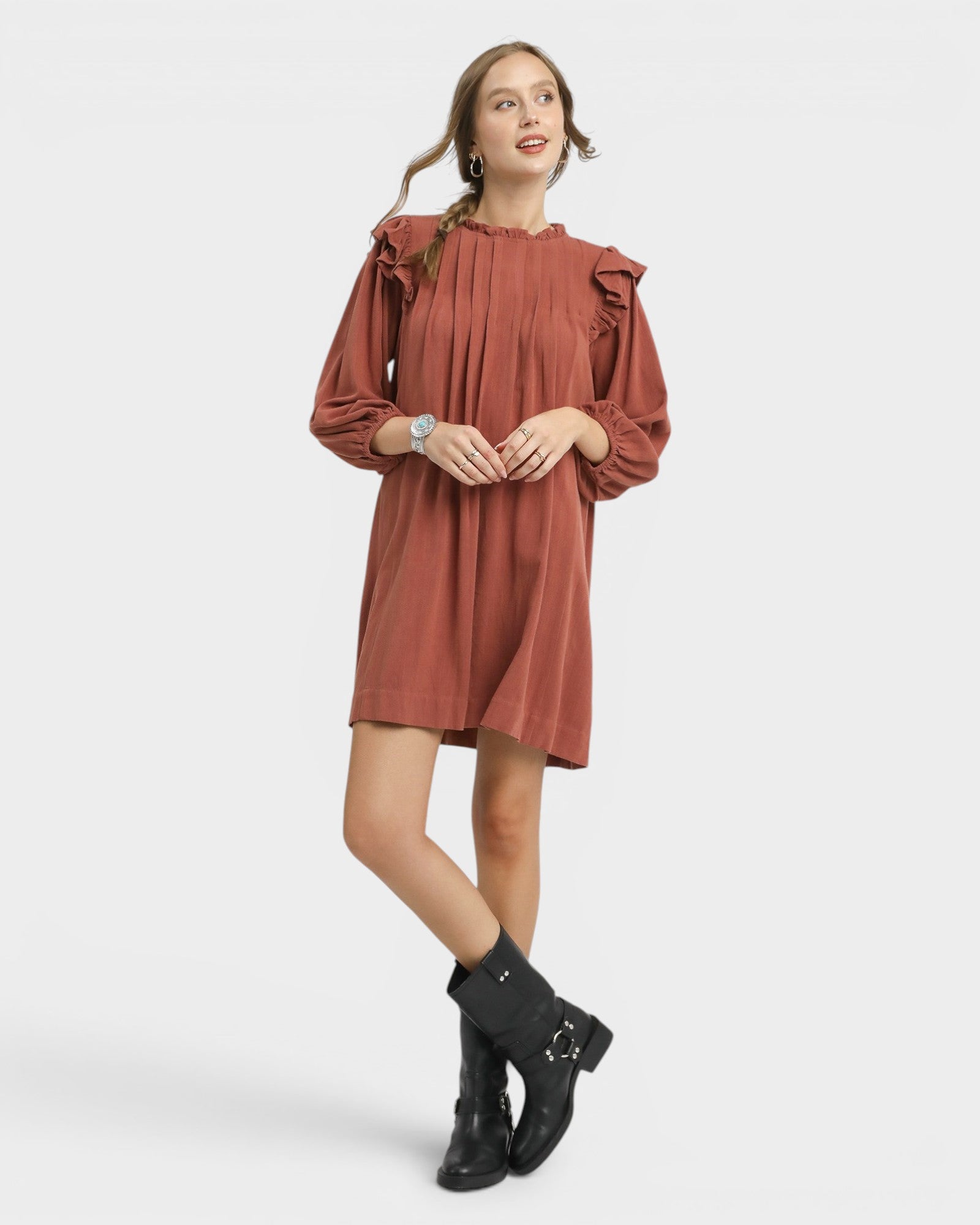 Woman wearing a rust-colored dress with ruffled sleeves on a white background