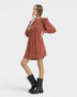 Woman wearing a rust-colored dress with puffed sleeves on a white background