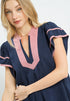 Woman wearing a navy dress with pink accents on a white background