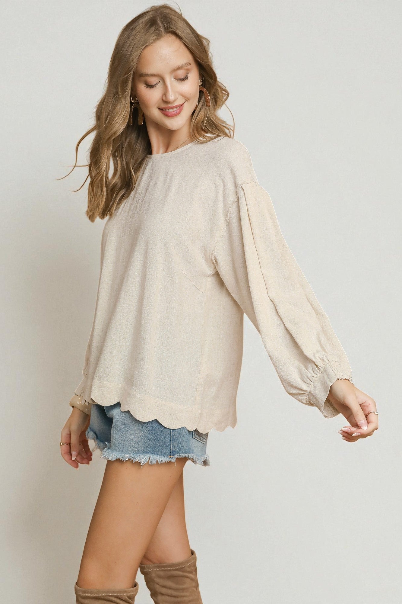 Woman wearing a beige blouse and denim skirt on a plain background