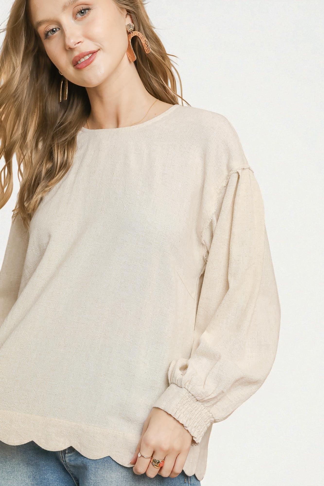 Woman wearing a beige sweater with a plain background