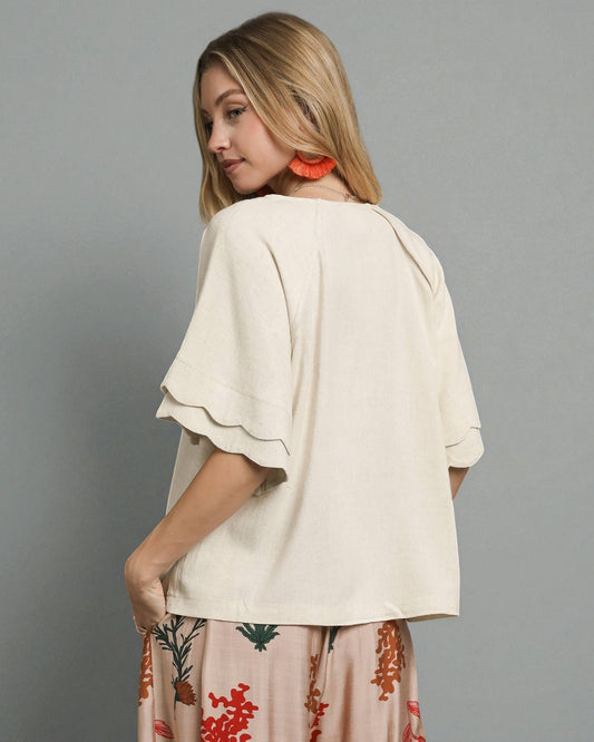 Woman wearing a beige top with floral skirt on a gray background