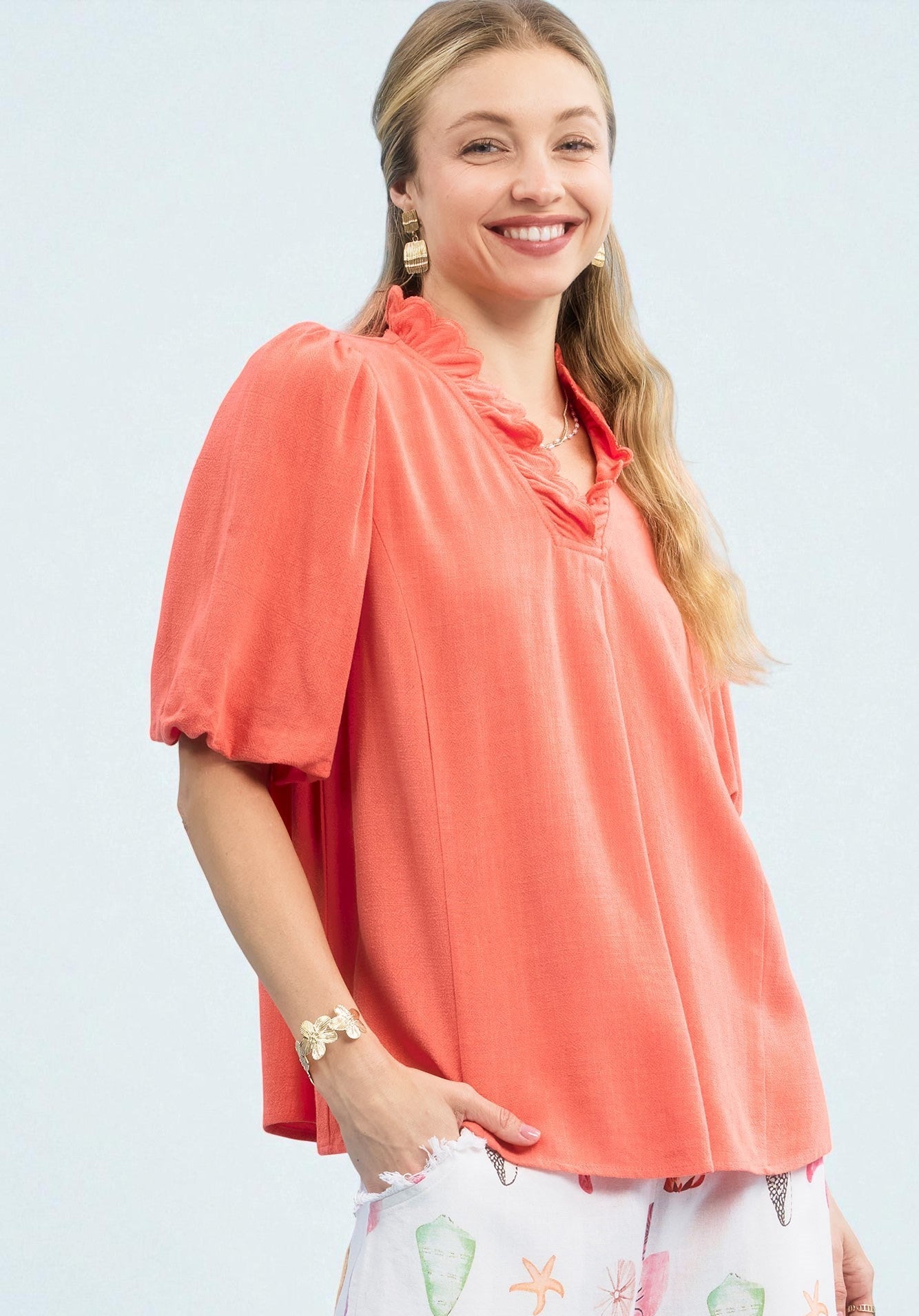 Woman wearing a coral blouse with a plain background