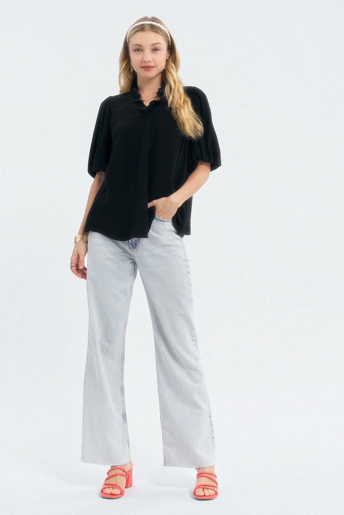 Woman wearing a black top and light blue jeans on a white background