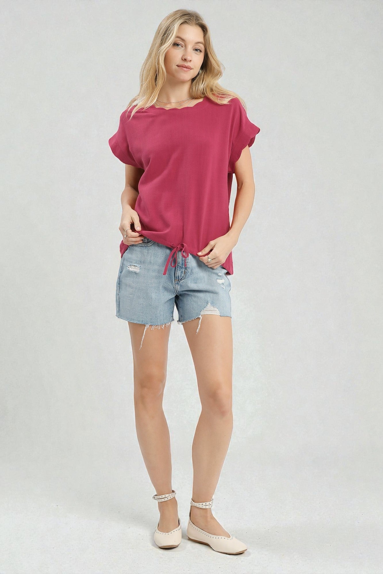 Woman wearing a pink top and denim shorts on a white background