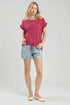 Woman wearing a pink top and denim shorts on a white background