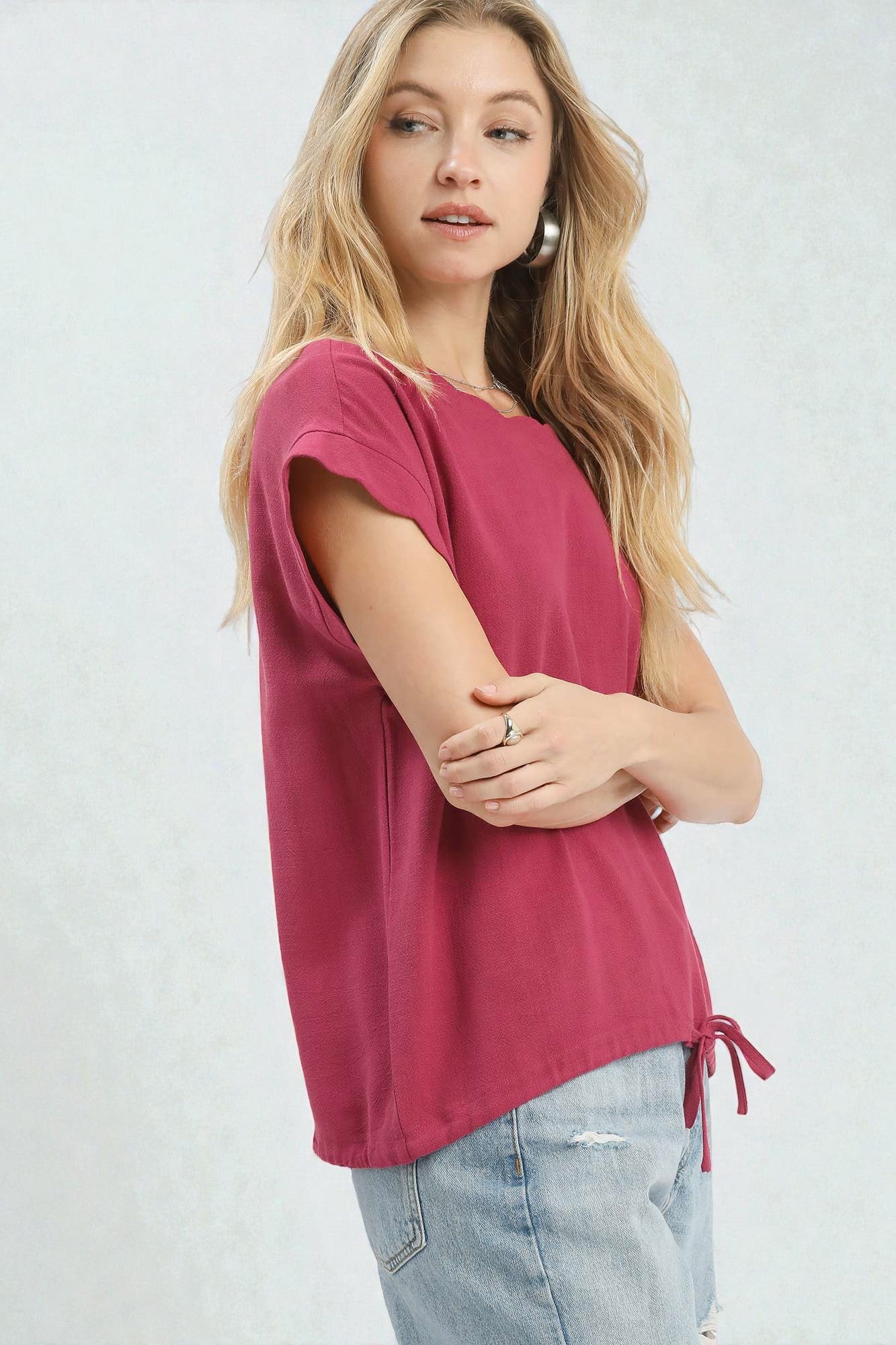 Woman wearing a pink t-shirt and light blue jeans on a white background