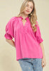Woman wearing a bright pink blouse with ruffled sleeves on a beige background