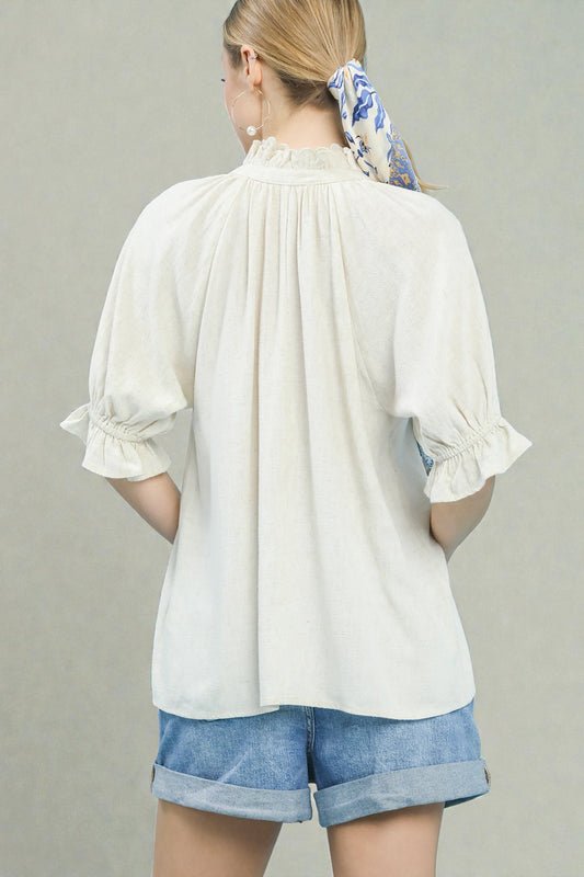 Woman wearing a white blouse and denim shorts with a gray background