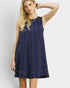 Woman wearing a navy blue sleeveless dress against a light gray background